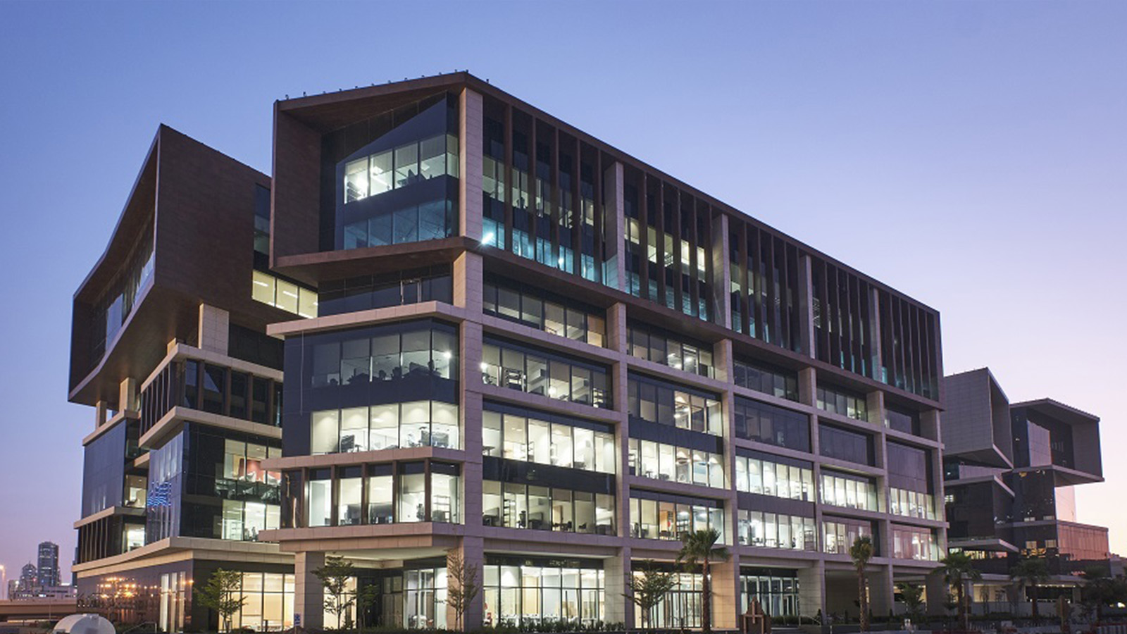 Modern multi-storey glass and concrete university building at dusk in Dubai.
