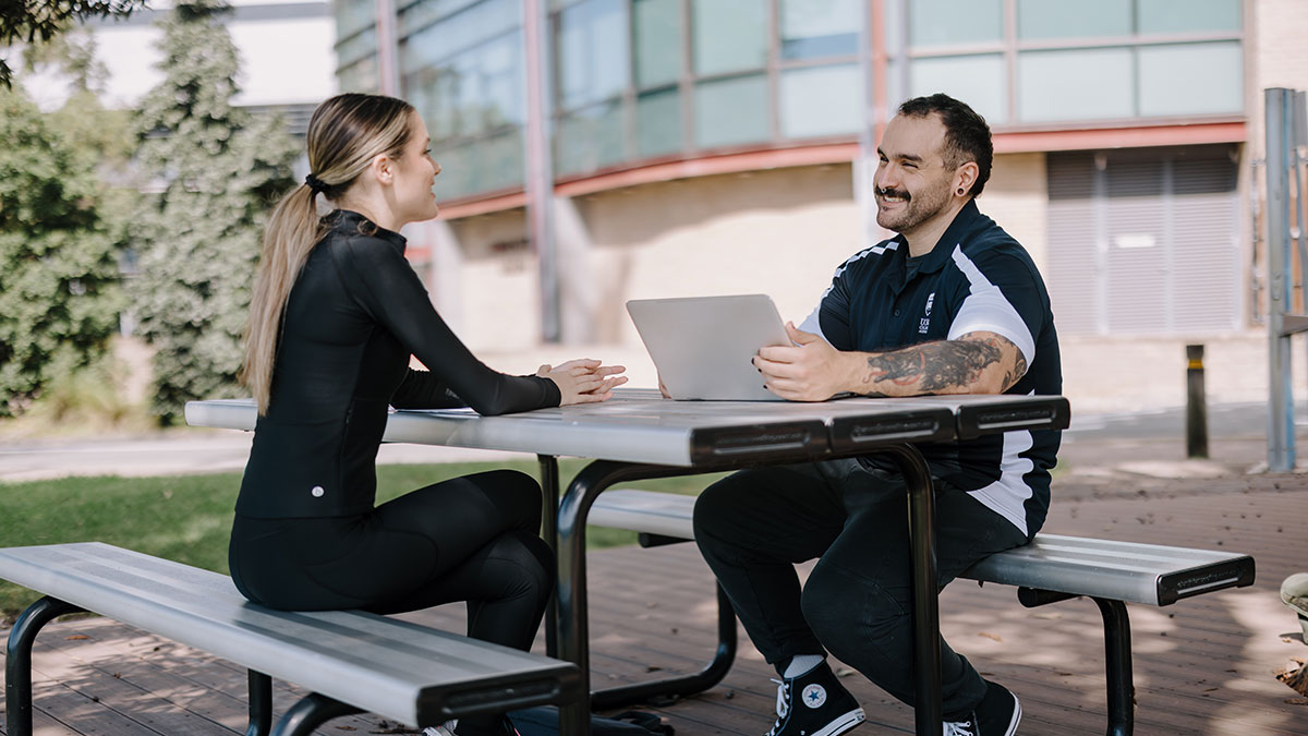Fitness students talking outside with laptop